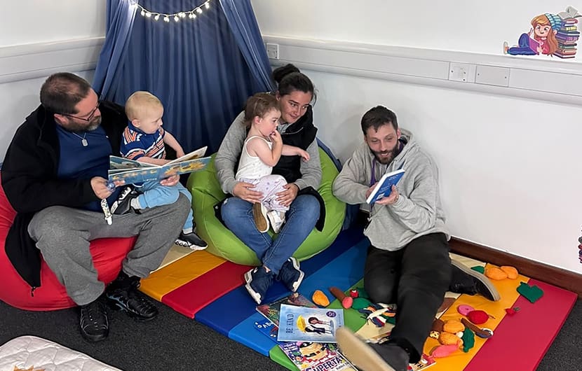 Storyteller Tom Burton (right) reading to young visitors in the new Cosy Corner at The Children's Foundation's Deckham Family Hub